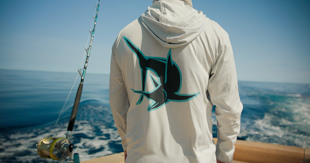 Back view of Marlin Mind hooded performance shirt with marlin graphic on a fishing boat